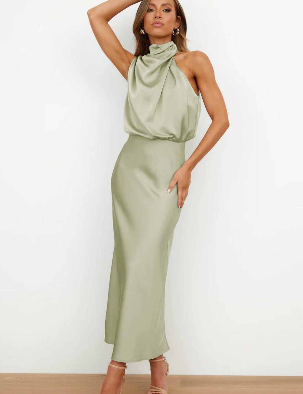 Abito lungo verde salvia in raso con collo alto drappeggiato, senza maniche, indossato da modella. Elegante e moderno, perfetto per eventi formali.
