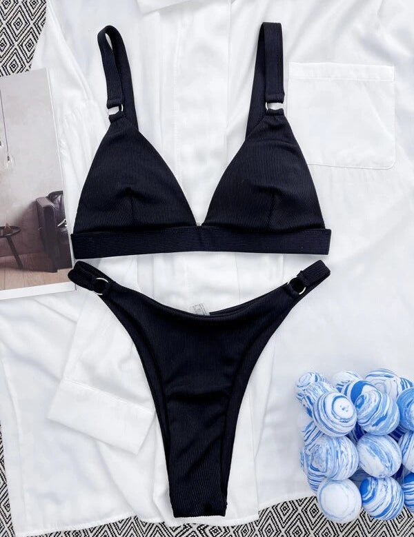 Bikini nero a due pezzi su sfondo bianco, design a triangolo, tessuto a costine, ideale per moda mare, estate, spiaggia, tendenze 2023.