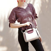 Donna con camicetta a pois rossi e borsa a tracolla bianca e bordeaux. Moda femminile, accessori eleganti, stile casual chic.