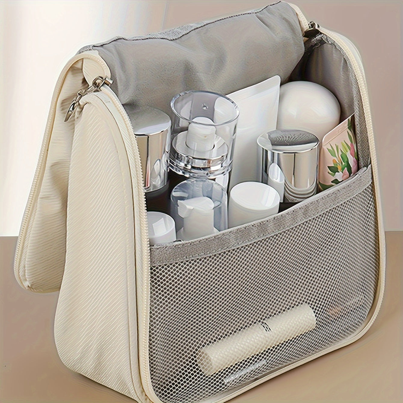 Beauty case da viaggio beige aperto, con scomparti organizzati contenenti flaconi cosmetici e accessori per la cura personale.