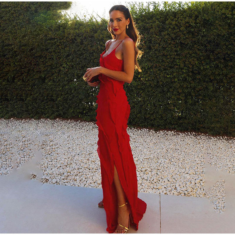Donna in abito lungo rosso elegante con spacco, posa all'aperto su sfondo di siepe verde. Moda femminile, abbigliamento estivo, stile glamour.
