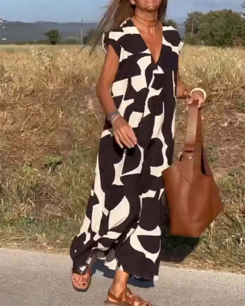 Donna con abito lungo bianco e nero astratto, borsa marrone, sandali, cammina su strada di campagna. Moda estiva, abbigliamento casual elegante.