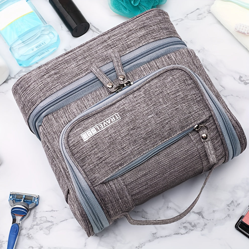 Borsa da viaggio grigia con zip multiple su sfondo di marmo, ideale per organizzare articoli da toeletta. Accessorio pratico e spazioso.