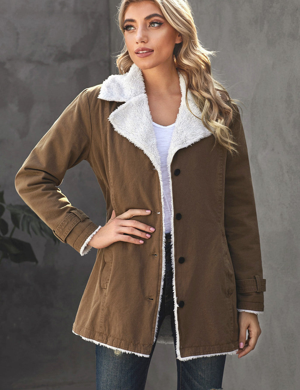 Giacca donna invernale marrone con fodera in pelliccia sintetica bianca, bottoni neri, indossata su maglia bianca e jeans strappati. Moda casual elegante.