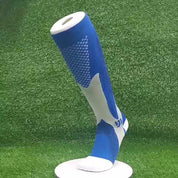 Calza a compressione blu e bianca su supporto, design sportivo, tessuto traspirante, ideale per attività fisica e recupero muscolare.