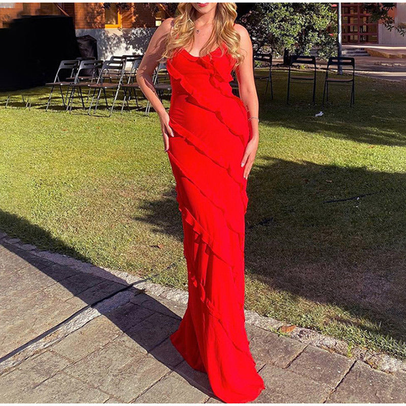Donna in abito lungo rosso elegante con volant, posa all'aperto su prato. Moda femminile, abbigliamento da sera, tendenza abiti cerimonia.