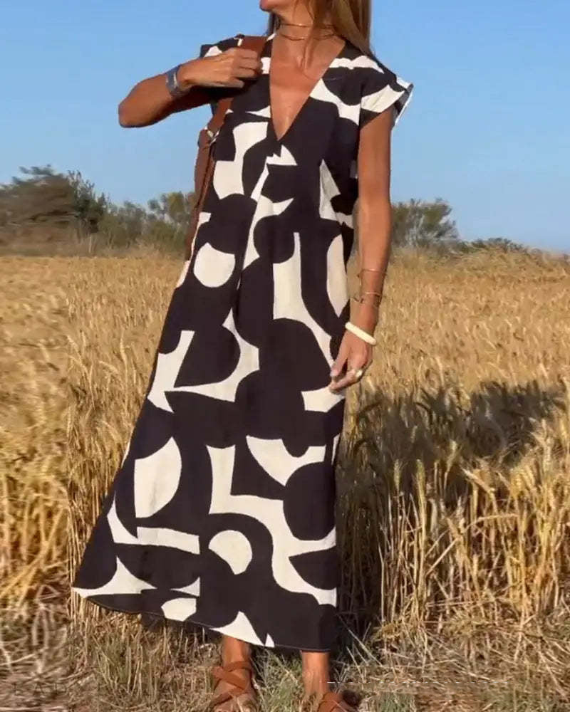 Donna in abito lungo estivo con stampa astratta bianco e nero, in un campo di grano. Moda femminile, abbigliamento casual elegante.