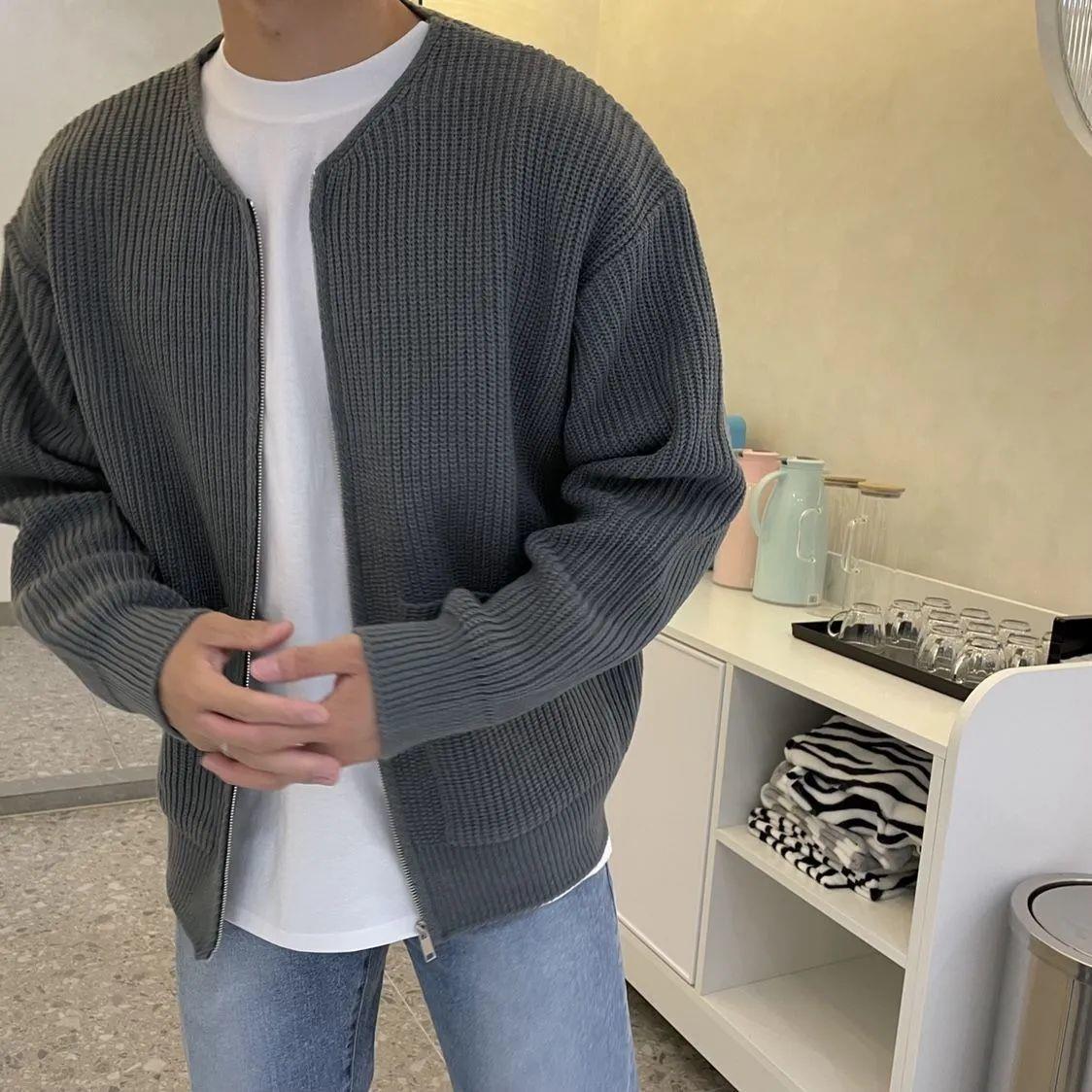 Uomo con cardigan grigio a maglia, t-shirt bianca e jeans chiari in cucina moderna. Stile casual, moda uomo autunno, abbigliamento confortevole.