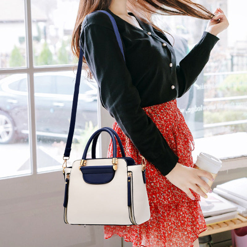 Donna con borsa a tracolla bianca e blu, indossa cardigan nero e gonna rossa a fiori, tiene una tazza da caffè. Moda casual elegante.