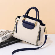 Borsa a mano elegante in pelle bianca e blu con dettagli dorati, tracolla regolabile, su sfondo neutro. Accessorio moda donna di lusso.