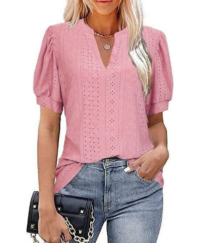 Blusa rosa in pizzo traforato, maniche corte a sbuffo, scollo a V, abbinata a jeans. Moda donna, abbigliamento estivo casual elegante.