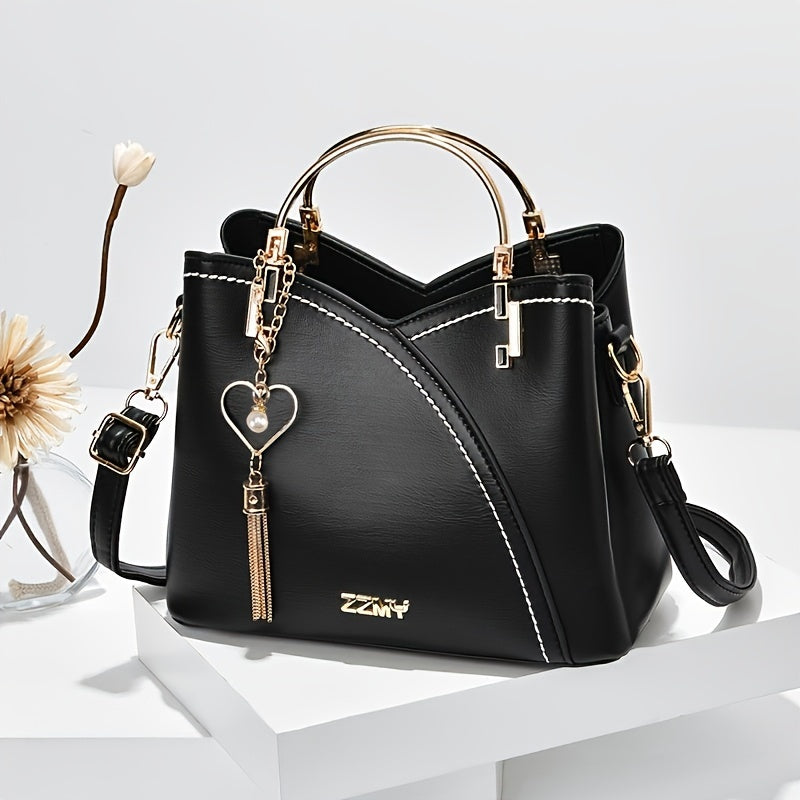 Borsa a mano in pelle nera con manici dorati, ciondolo a cuore e tracolla regolabile. Design elegante, ideale per moda femminile e accessori di lusso.