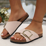 Sandali donna in pelle beige con fibbia dorata, suola in sughero, indossati all'aperto. Scarpe estive eleganti e comode.