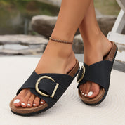 Sandali donna neri con fibbia dorata, suola in sughero, indossati su sfondo esterno. Scarpe estive eleganti e comode, moda casual.