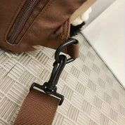 Gancio in plastica nera su borsa marrone, dettaglio di chiusura sicura. Accessorio moda, zaino resistente, design funzionale.