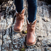 Stivali in pelle marrone su roccia, scarpe invernali da donna, moda outdoor, calzature resistenti, comfort e stile, escursionismo autunnale.