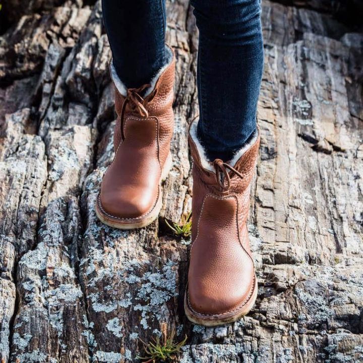 Stivali in pelle marrone su roccia, scarpe invernali da donna, moda outdoor, calzature resistenti, comfort e stile, escursionismo autunnale.