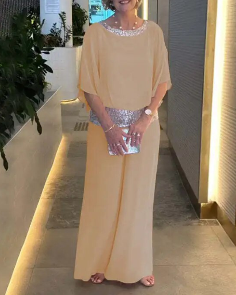 Abito elegante donna color pesca con paillettes, clutch argento, indossato in corridoio moderno. Moda serale, abbigliamento formale.
