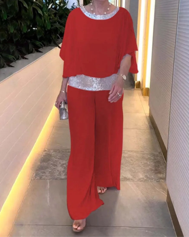 Donna in elegante completo rosso con dettagli argentati, cammina in corridoio moderno. Moda donna, abbigliamento serale, stile sofisticato.