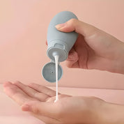 Mano che versa lozione bianca da flacone grigio su sfondo rosa. Cura della pelle, idratazione, cosmetici, bellezza quotidiana.