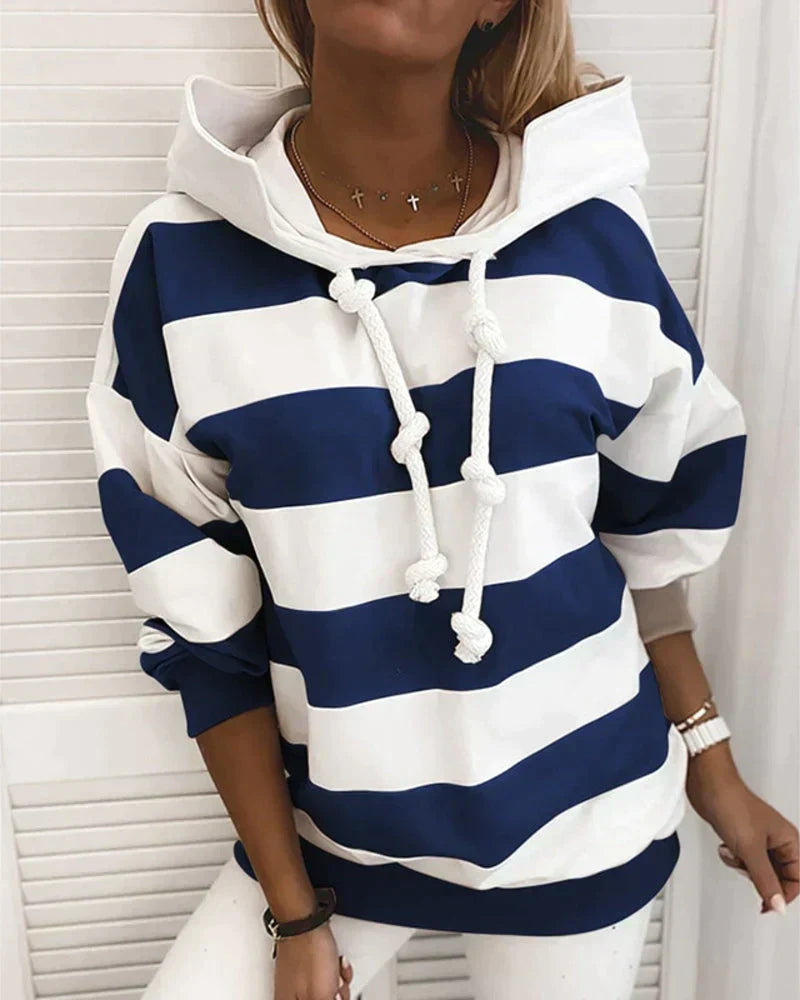 Felpa a righe blu e bianche con cappuccio e lacci, indossata da una donna. Stile casual, moda autunnale, abbigliamento femminile trendy.