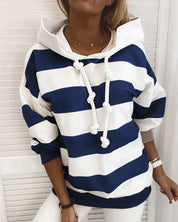 Felpa a righe blu e bianche con cappuccio e lacci, indossata da una donna. Stile casual, moda autunnale, abbigliamento femminile trendy.