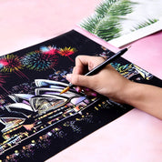 Mano che disegna su carta nera con grattacieli e fuochi d'artificio, penna dorata, arte creativa, skyline notturno, disegno artistico dettagliato.