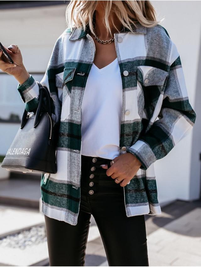 Donna con camicia a quadri verde e bianca, pantaloni neri, borsa Balenciaga, smartphone in mano. Moda autunnale casual chic.