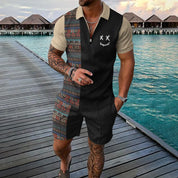 Tuta estiva da uomo con motivo etnico, maniche corte, zip frontale, indossata su passerella in legno vicino al mare. Moda casual estiva.