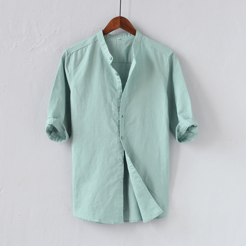 Camicia uomo verde menta, maniche lunghe arrotolate, colletto alla coreana, tessuto leggero, appesa su gruccia di legno, moda casual elegante.
