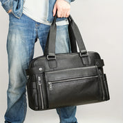 Uomo con borsa a tracolla in pelle nera, tasche con zip, design elegante, moda casual, jeans, accessorio maschile, stile urbano.