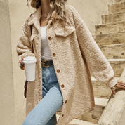 Giacca in pile beige oversize con bottoni, indossata su top bianco e jeans chiari. Donna su scala con caffè. Moda autunnale casual.