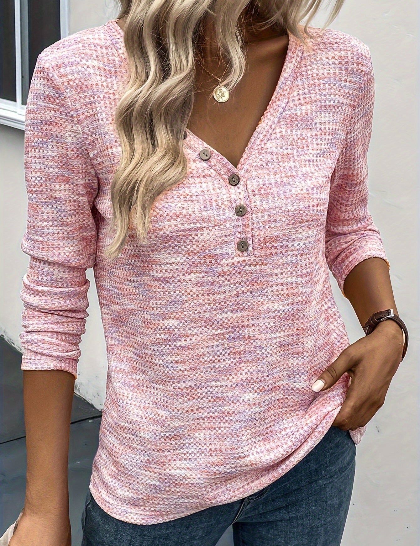 Maglia donna rosa a maniche lunghe con scollo a V e bottoni, tessuto lavorato a maglia, indossata con jeans. Look casual e alla moda.