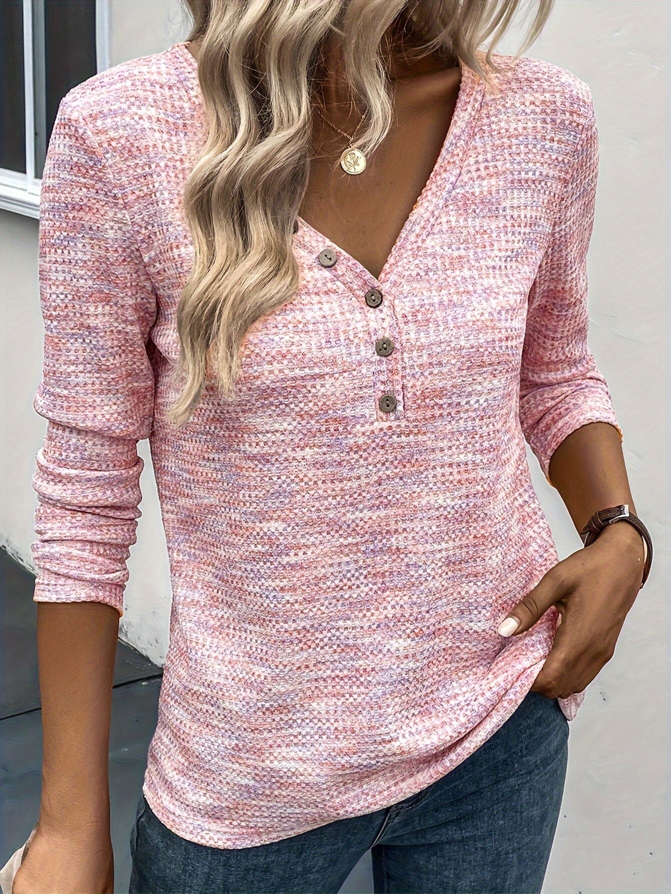 Maglia donna rosa a maniche lunghe con scollo a V e bottoni, tessuto lavorato a maglia, indossata con jeans. Look casual e alla moda.