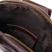 Interno di uno zaino in pelle marrone con cerniera aperta, tasca interna visibile. Design elegante e spazioso, ideale per viaggi e lavoro.