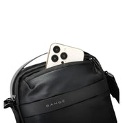 Borsa a tracolla nera Bange con smartphone bianco in tasca frontale. Design elegante, ideale per viaggi e uso quotidiano. Accessori moda uomo.