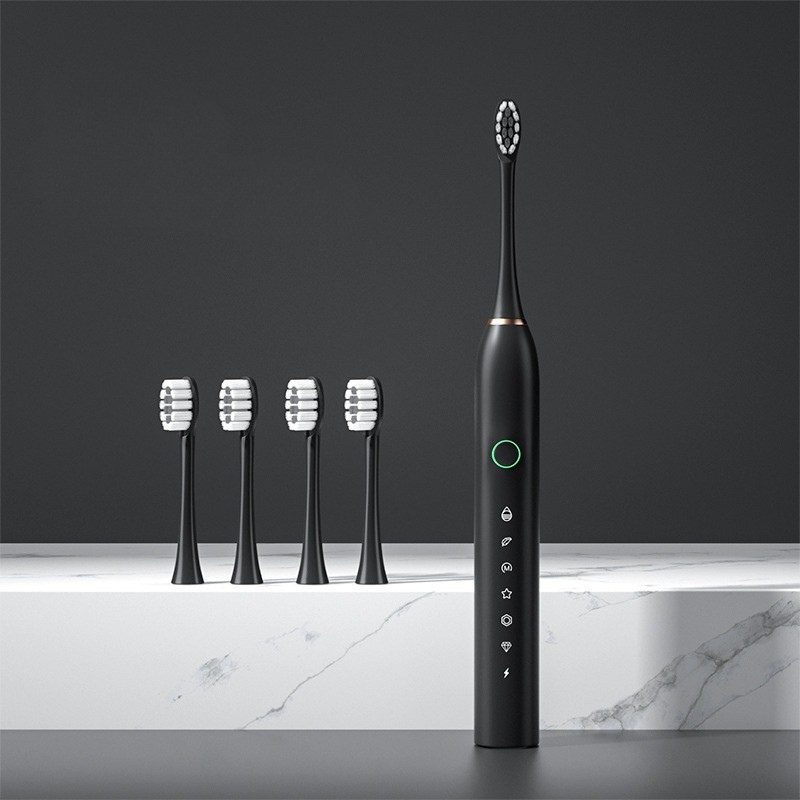 Spazzolino elettrico nero con cinque testine di ricambio su sfondo grigio. Design moderno, tecnologia avanzata per igiene orale efficace.