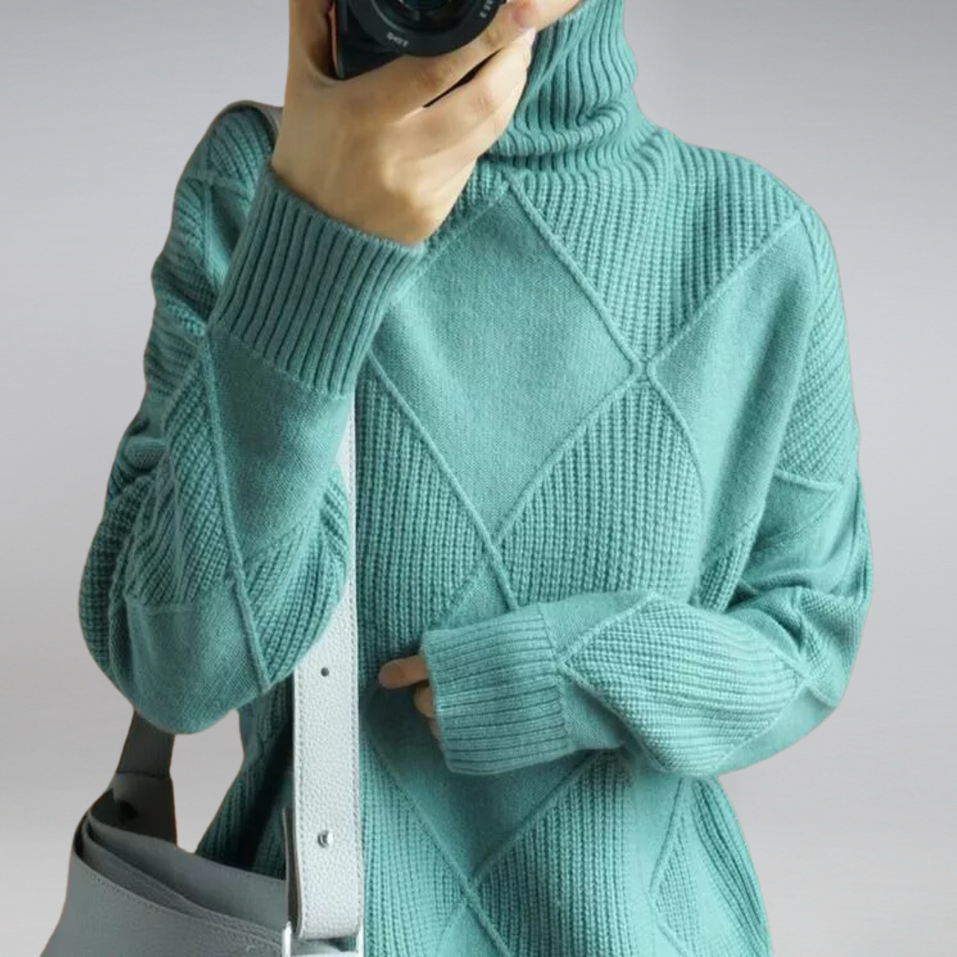 Maglione donna verde acqua a collo alto con motivo geometrico, abbinato a borsa grigia. Moda autunnale, abbigliamento casual elegante.