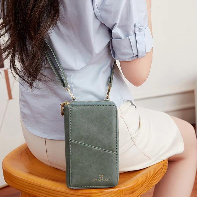 Borsa a tracolla verde in pelle, design elegante, indossata da donna seduta. Accessorio moda femminile, ideale per uso quotidiano.