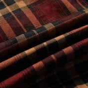 Tessuto scozzese in lana, motivo a quadri rosso e nero, texture morbida e calda, ideale per abbigliamento invernale e accessori moda.