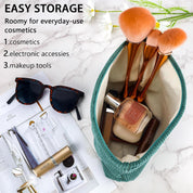 Borsa cosmetica verde con pennelli trucco, occhiali da sole e accessori su rivista. Ideale per cosmetici, accessori elettronici e strumenti trucco.