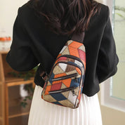 Zaino a tracolla multicolore con motivo geometrico, indossato da una donna. Design moderno, ideale per moda urbana e viaggi.