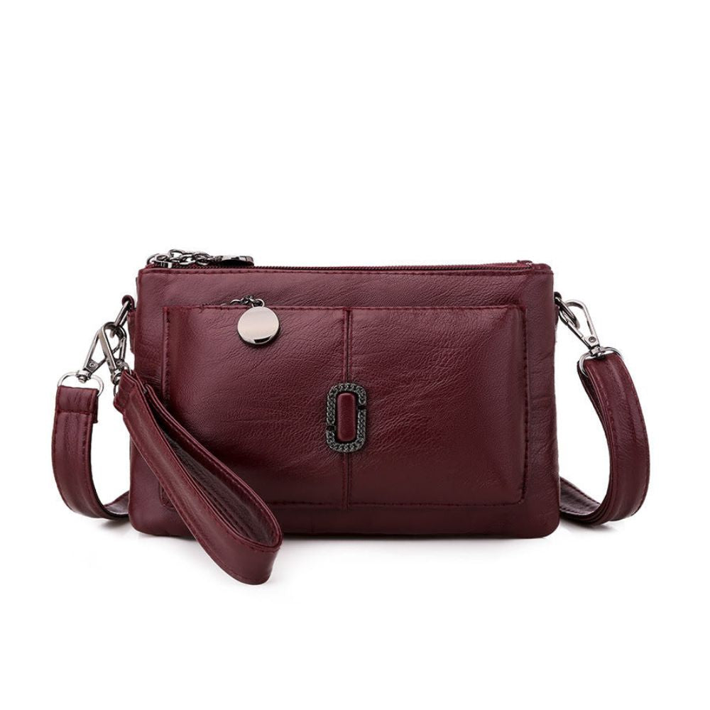 Borsa a tracolla in pelle bordeaux con cerniera, tasca frontale e tracolla regolabile. Elegante accessorio moda donna.
