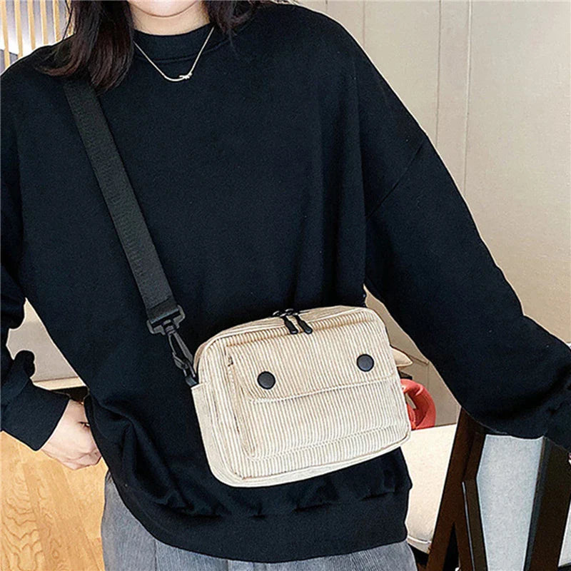 Borsa a tracolla beige in tessuto a coste, indossata da una persona con maglia nera. Accessorio moda casual, ideale per uso quotidiano.