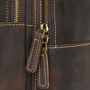 Zaino in pelle marrone con cerniere robuste e cuciture a contrasto, design elegante e resistente, ideale per viaggi e uso quotidiano.