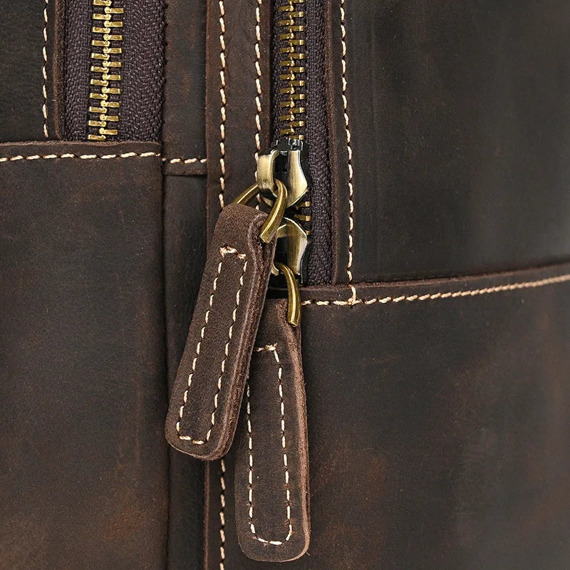 Zaino in pelle marrone con cerniere robuste e cuciture a contrasto, design elegante e resistente, ideale per viaggi e uso quotidiano.