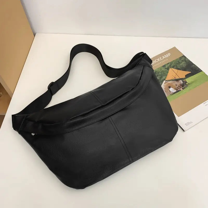 Borsa a tracolla nera in pelle su tavolo bianco, design moderno ed elegante, ideale per uomo e donna. Accessorio moda versatile e di tendenza.