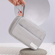 Borsa da viaggio grigia in tessuto, con manico, su sfondo minimalista. Ideale per organizzare accessori. Design elegante e funzionale.