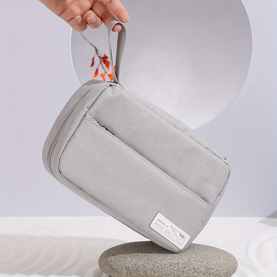 Borsa da viaggio grigia in tessuto, con manico, su sfondo minimalista. Ideale per organizzare accessori. Design elegante e funzionale.