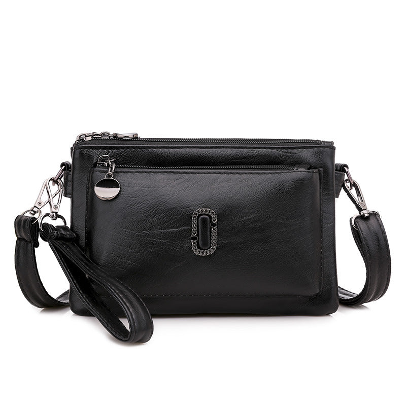 Borsa a tracolla in pelle nera con cerniera, tasca frontale, logo decorativo e cinturino regolabile. Elegante e versatile per ogni occasione.